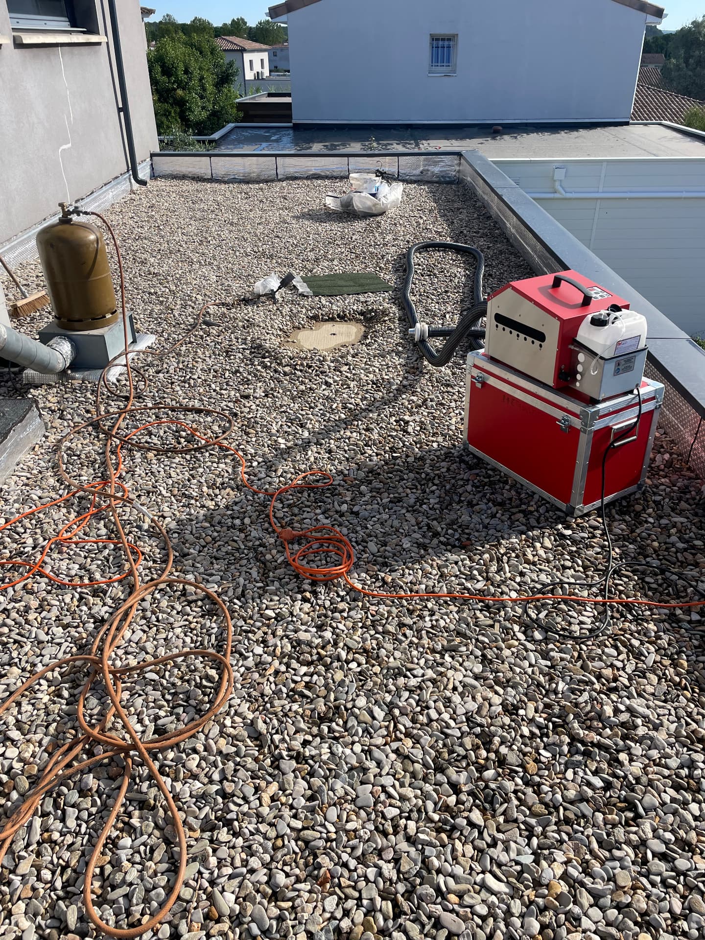 Générateur de fumée et bouteille de gaz installés sur une toiture-terrasse gravillonnée