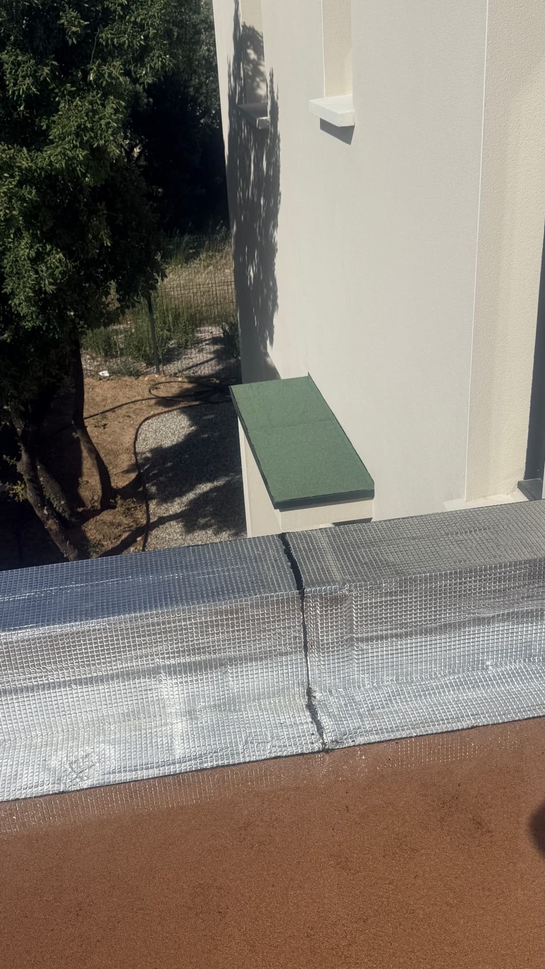 Détail d'un relevé d'acrotère fini en bande autoprotégée aluminium sur toiture-terrasse