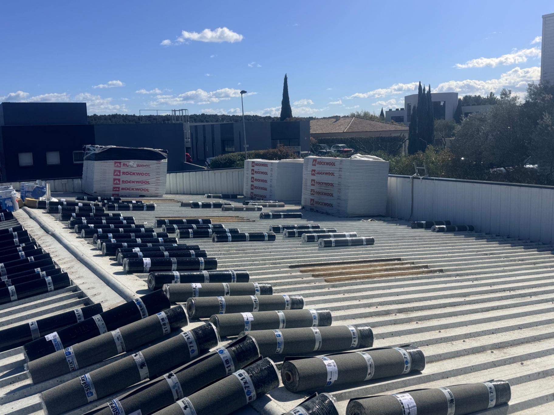 Approvisionnement du chantier : rouleaux d'étanchéité et panneaux isolants Rockwool sur le bac acier