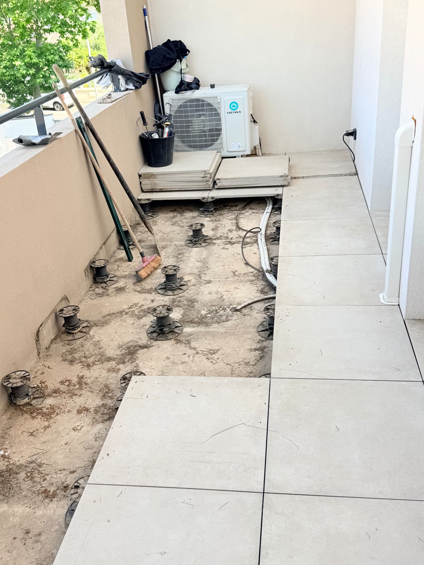 Balcon d'appartement en cours de dépose : dalles sur plots retirées et support dégradé mis à nu