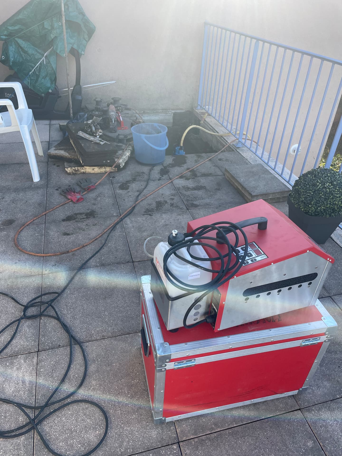 Gros plan du générateur de fumée rouge posé sur une terrasse carrelée pendant la recherche de fuite