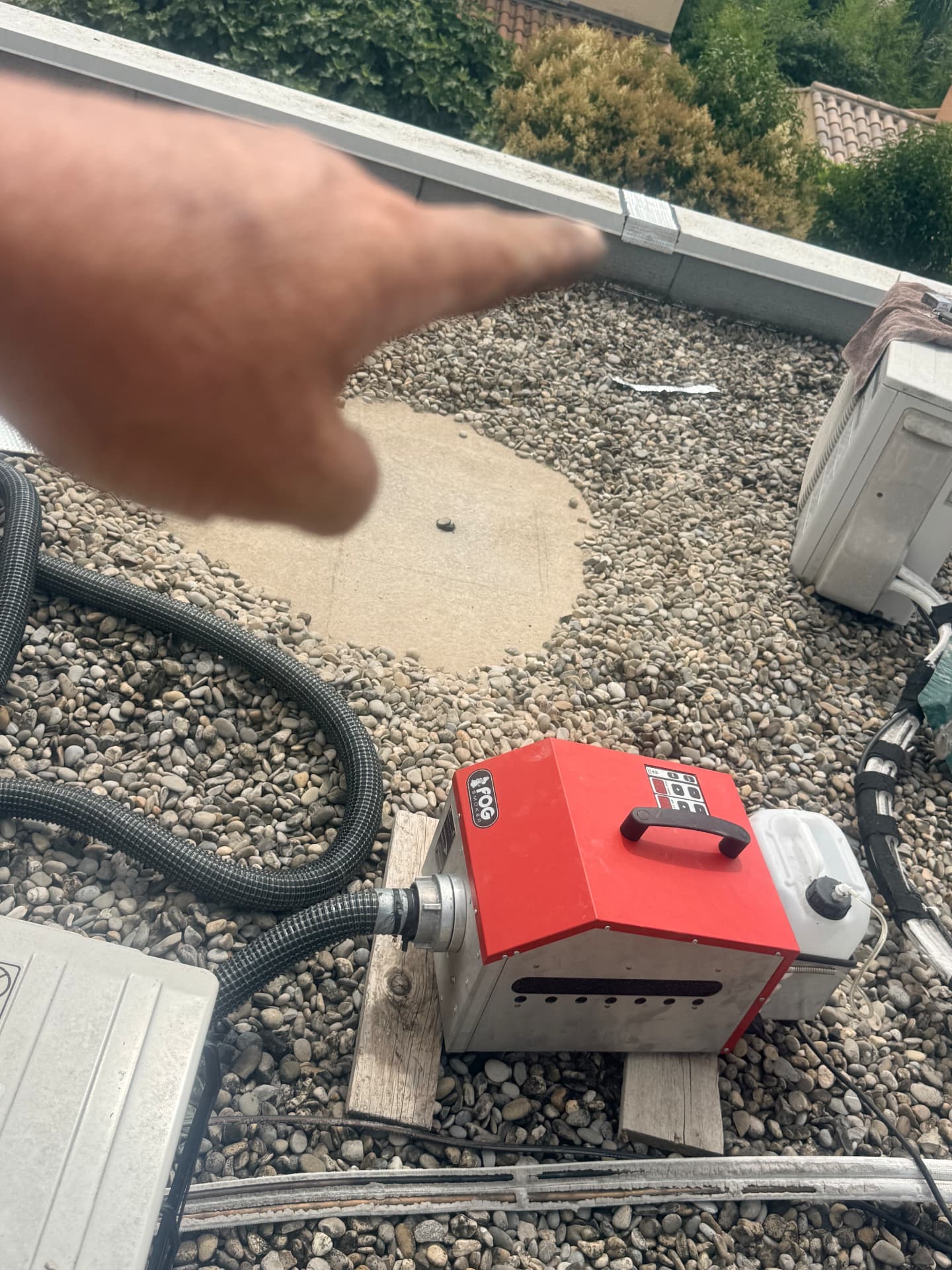 Générateur de fumée rouge en action sur une toiture-terrasse gravillonnée pour localiser une fuite