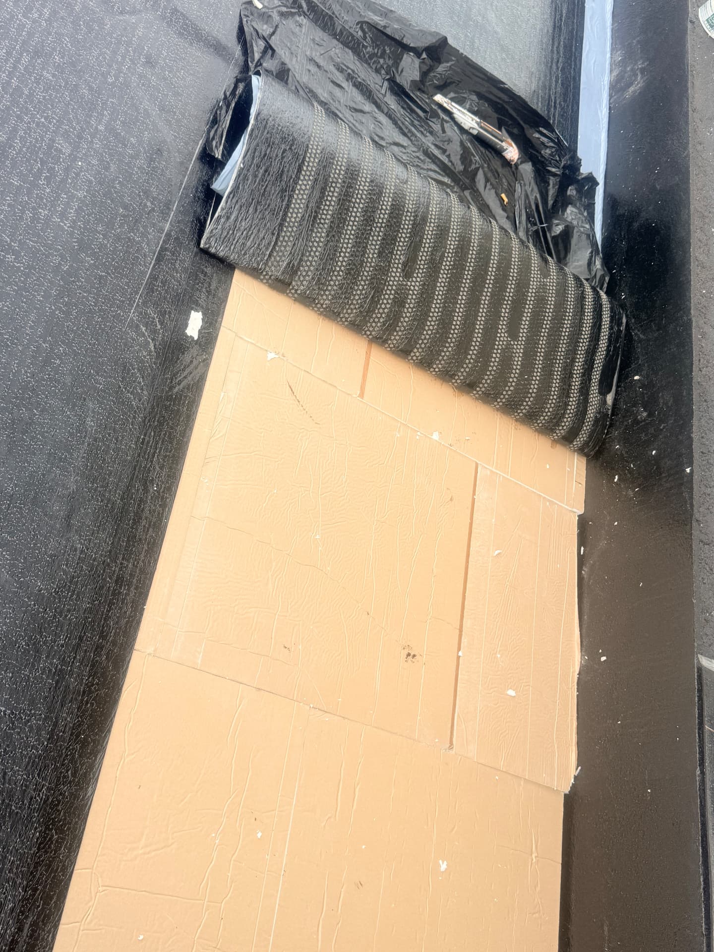 Rouleau de membrane d'étanchéité et panneaux isolants en cours de pose sur la terrasse